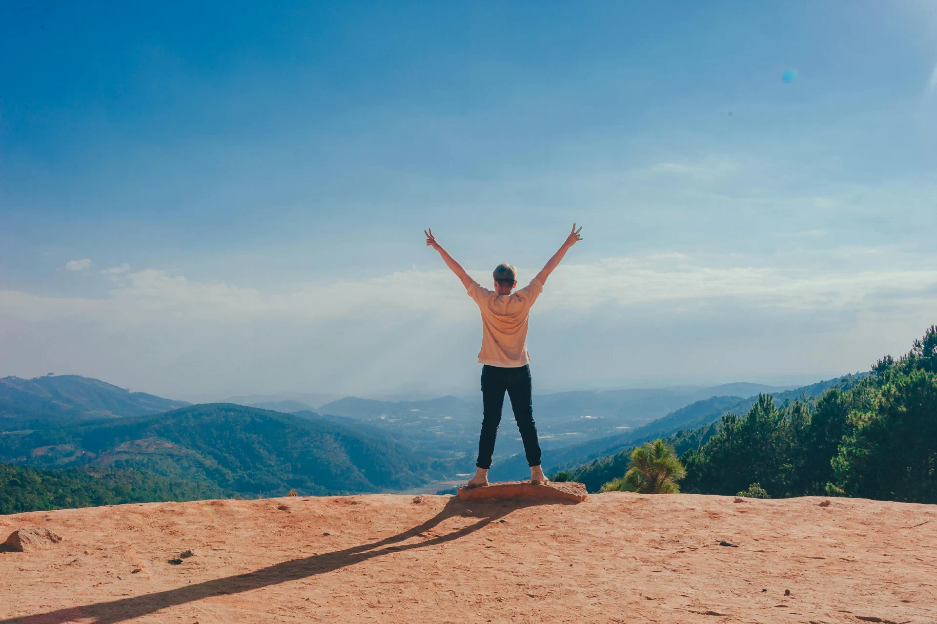 Foto met vrouw die juichend op de rand van een klif staat, door Min An van Pexels: https://www.pexels.com/photo/woman-standing-on-cliff-1134190/